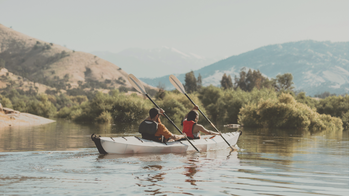 Friends kayaking on a lake near their RV boondocking site, celebrating off-grid RV travel and outdoor exploration.